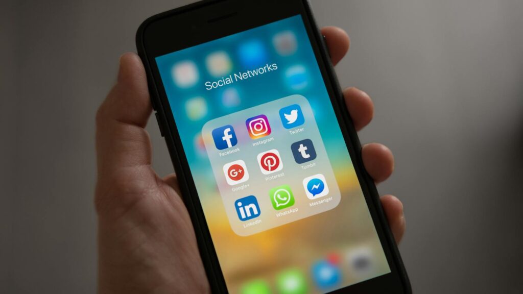 A smartphone displaying various social media icons held in a hand, showcasing modern communication apps.