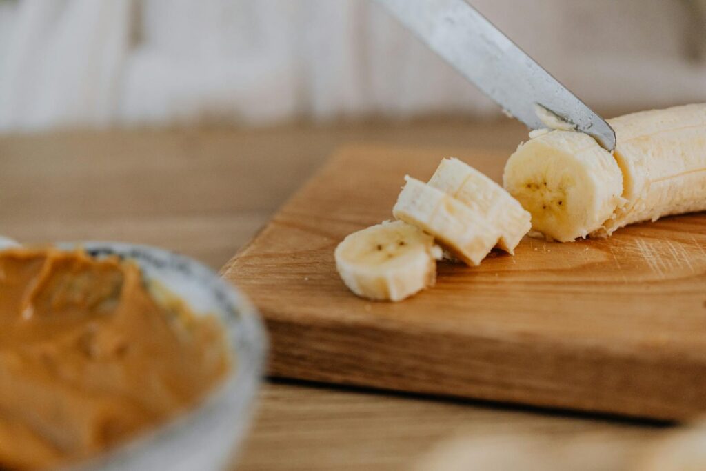 Close-up of a banana being sliced on a wooden board, ideal for healthy snack visuals.
