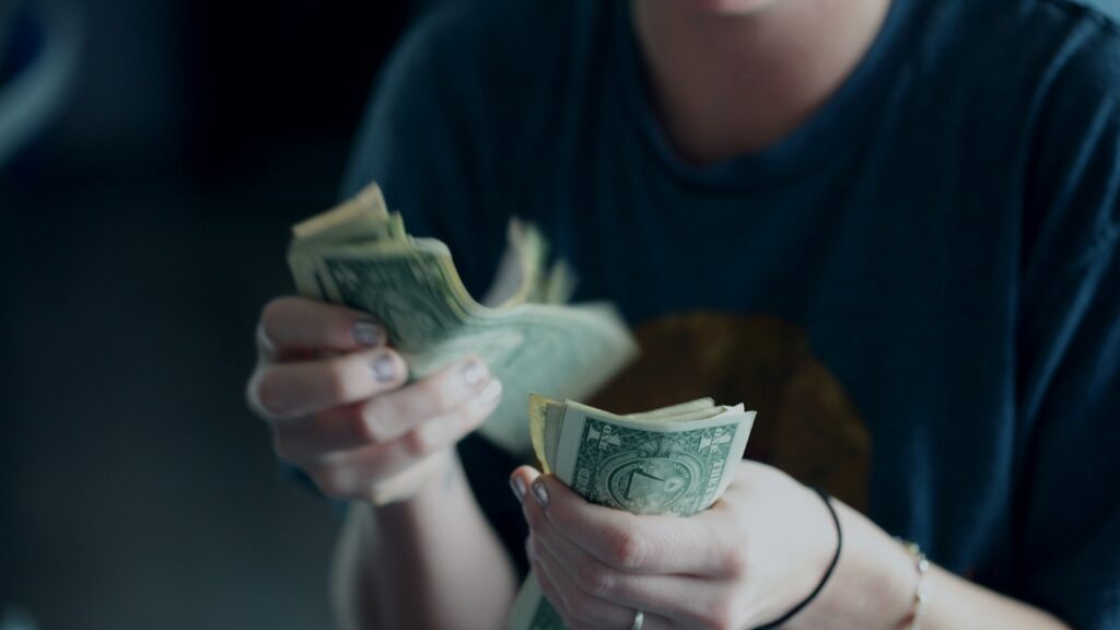 Focus photography of person counting dollar banknotes.