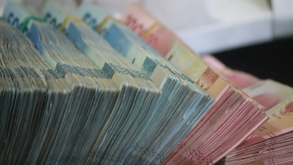 A close-up of bundled banknotes of various denominations, showing different colors and values.