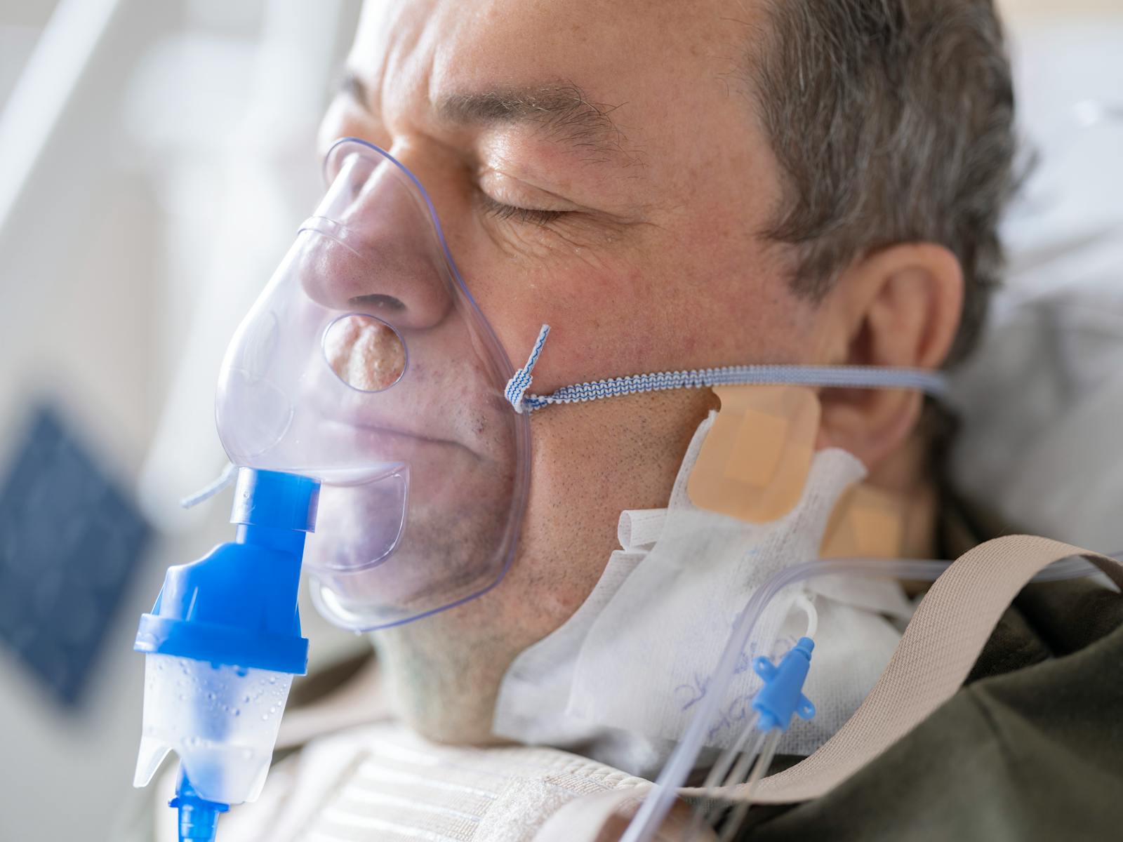 Close-up of a senior patient wearing an oxygen mask in a hospital setting.